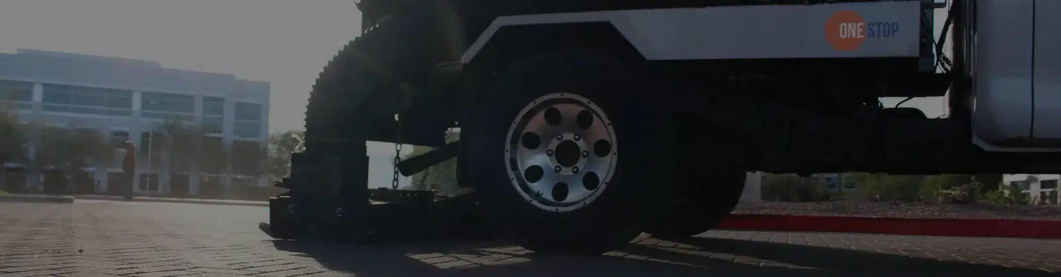 Close-up of a One Stop Property Services street sweeping truck cleaning a commercial parking lot