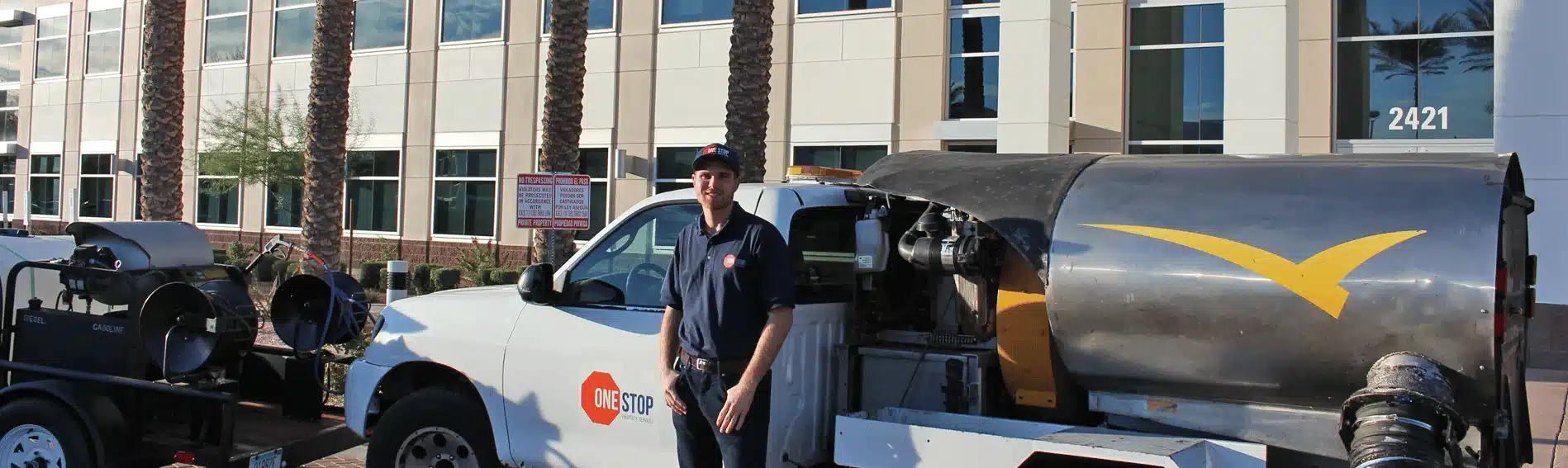 One Stop Property Services employee standing next to a specialized cleaning truck outside a modern commercial building