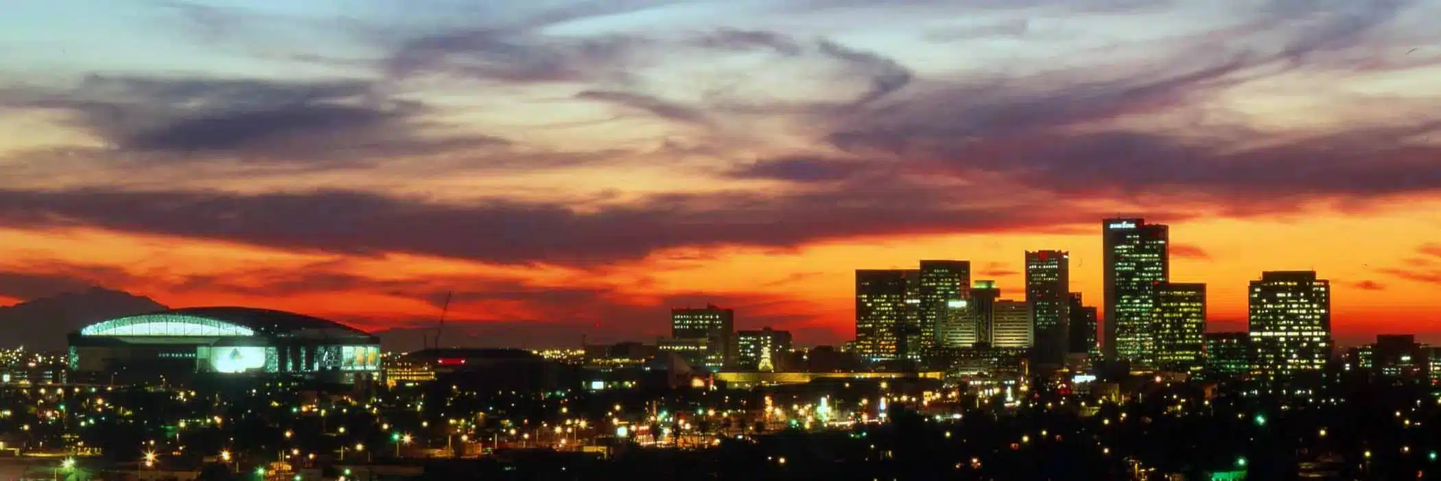 Colorful Phoenix skyline at dusk with city lights and a glowing sunset sky